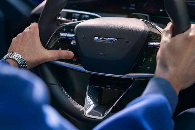 Close-up of a Man About to Press the V-Button on the 2026 OPTIQ-V Steering Wheel | Jim Shorkey Cadillac in Gainesville GA